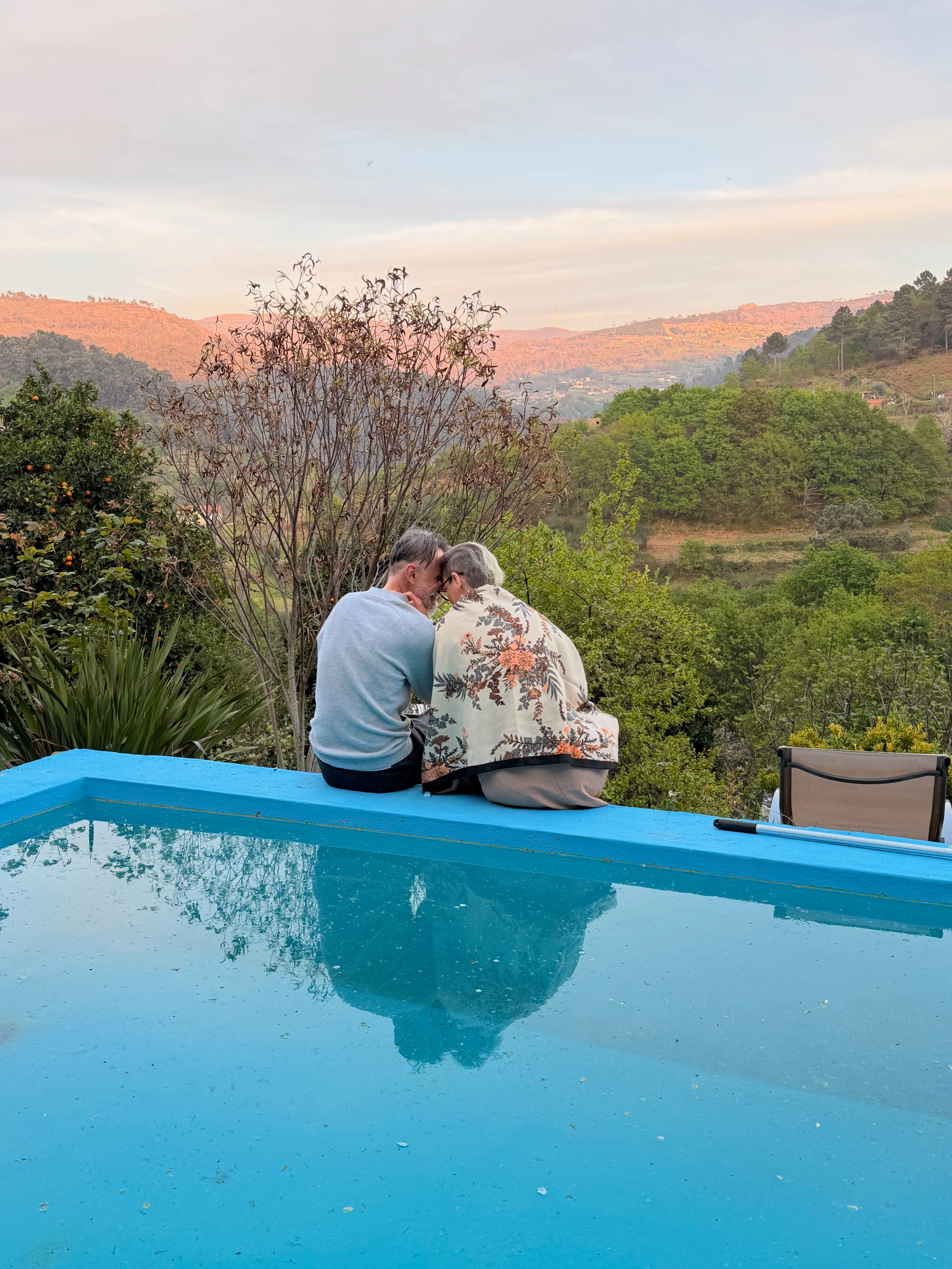 Rita & Sandro sentado à beira da piscina com vista para a paisagem.